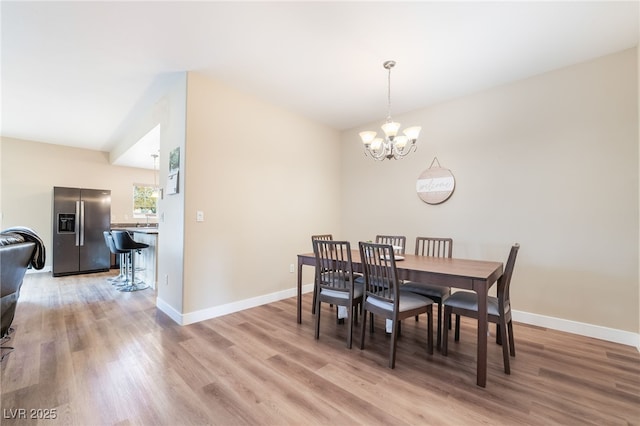 dining space featuring light wood-type flooring, baseboards, and a notable chandelier