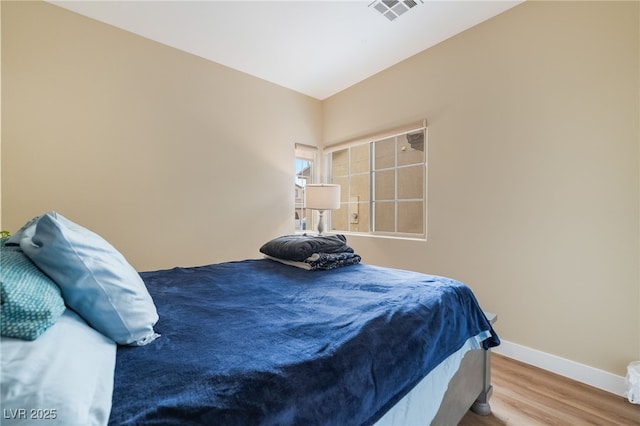 bedroom with visible vents, baseboards, and wood finished floors