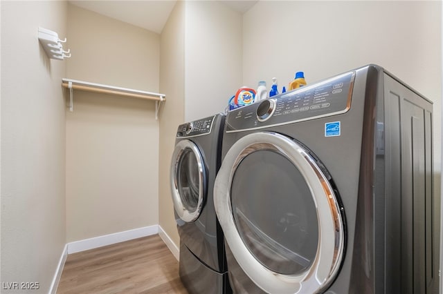 clothes washing area featuring laundry area, independent washer and dryer, baseboards, and light wood-style floors