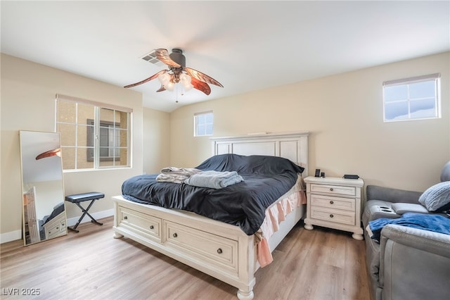 bedroom featuring a ceiling fan, visible vents, baseboards, and light wood finished floors