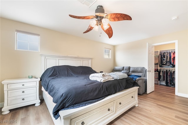 bedroom featuring a spacious closet, visible vents, ceiling fan, and light wood-style floors