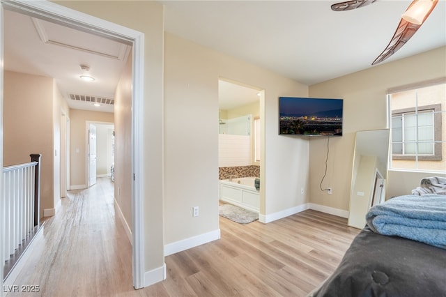 bedroom featuring baseboards, visible vents, light wood finished floors, attic access, and connected bathroom