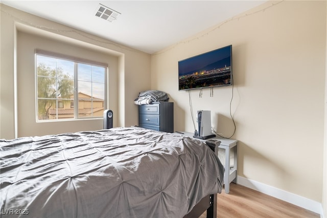 bedroom featuring visible vents, baseboards, and wood finished floors