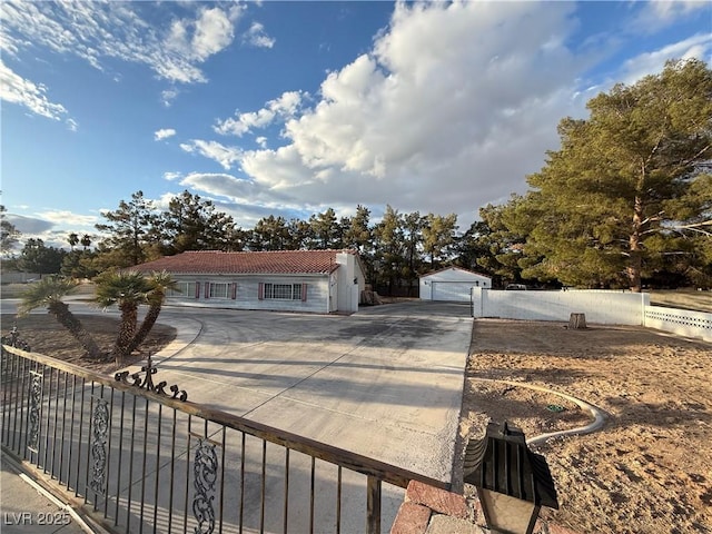 view of front of home with a detached garage, an outbuilding, and fence