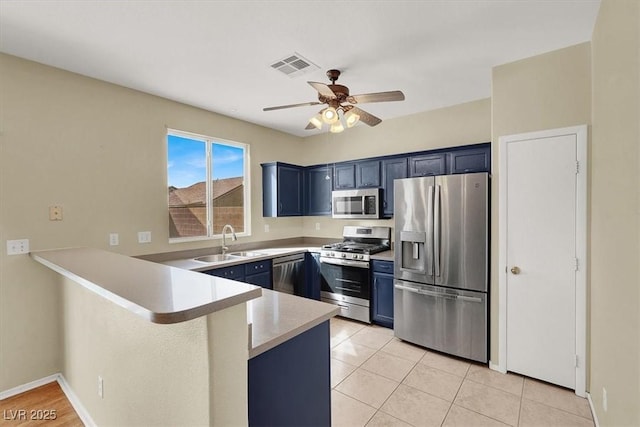 kitchen featuring visible vents, blue cabinetry, a sink, stainless steel appliances, and a peninsula