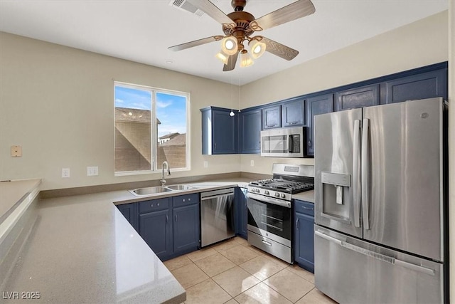 kitchen with light tile patterned flooring, a sink, light countertops, appliances with stainless steel finishes, and blue cabinets