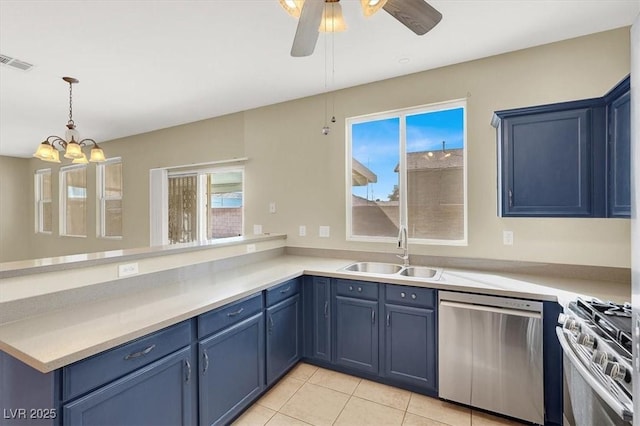 kitchen featuring visible vents, a peninsula, blue cabinetry, a sink, and stainless steel appliances