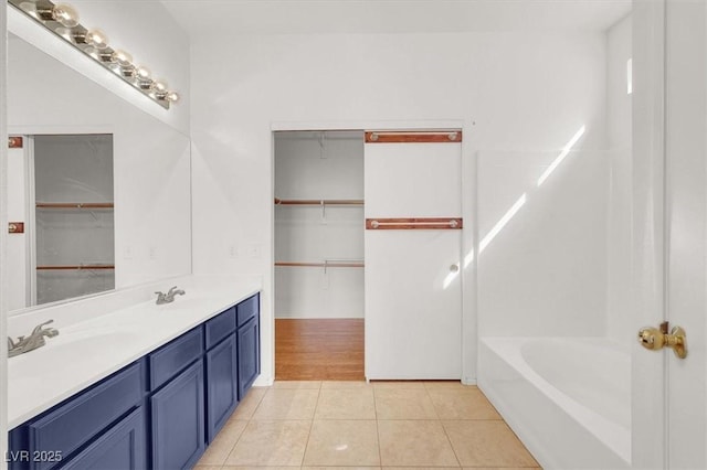 bathroom featuring double vanity, a walk in closet, shower / washtub combination, and tile patterned flooring