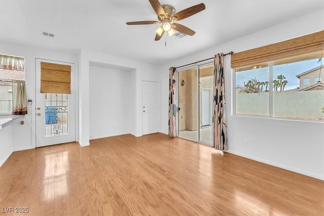 interior space featuring visible vents, baseboards, a ceiling fan, and wood finished floors