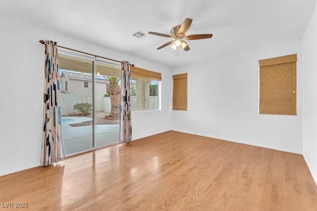 spare room featuring visible vents, baseboards, a ceiling fan, and wood finished floors