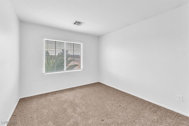 carpeted empty room featuring baseboards and visible vents