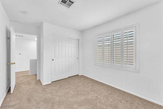 unfurnished bedroom with a closet, visible vents, baseboards, and carpet