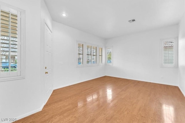 unfurnished room featuring visible vents, baseboards, and wood finished floors