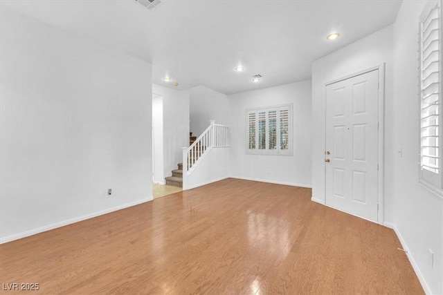 unfurnished room featuring stairs, recessed lighting, wood finished floors, and baseboards