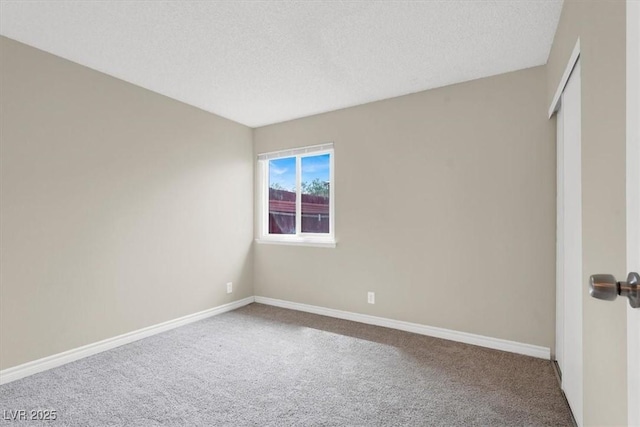 spare room with baseboards, carpet floors, and a textured ceiling