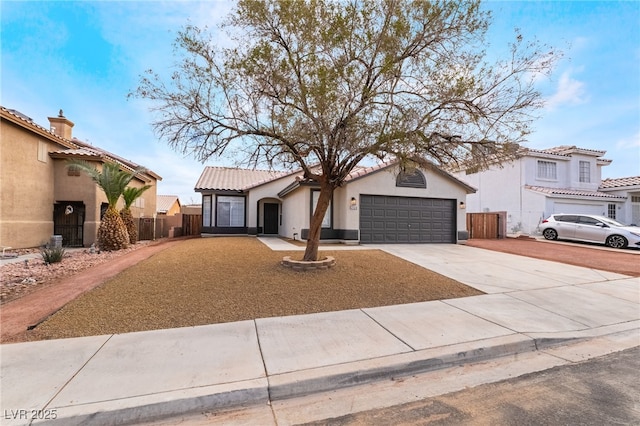 mediterranean / spanish-style house featuring stucco siding, driveway, a tile roof, fence, and a garage