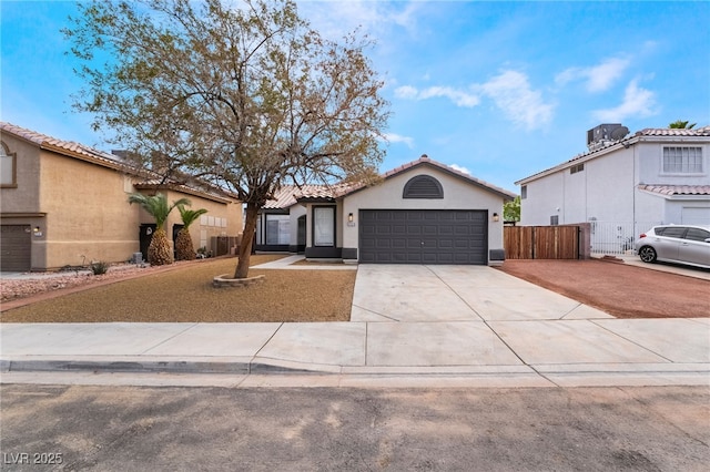 mediterranean / spanish-style home featuring stucco siding, driveway, a tile roof, fence, and a garage