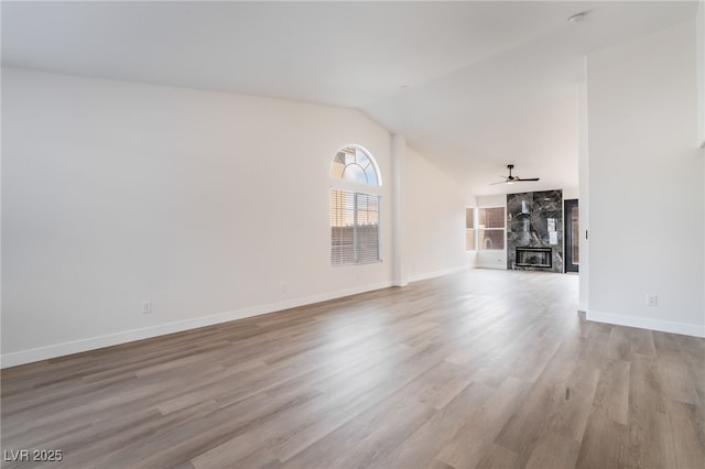 unfurnished living room with a large fireplace, baseboards, ceiling fan, vaulted ceiling, and wood finished floors