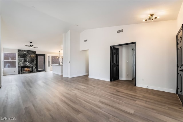 unfurnished living room featuring visible vents, wood finished floors, lofted ceiling, and a premium fireplace