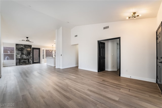 unfurnished living room featuring visible vents, a fireplace, lofted ceiling, and wood finished floors