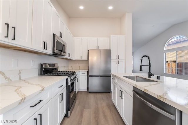 kitchen featuring a sink, appliances with stainless steel finishes, white cabinets, and light wood finished floors