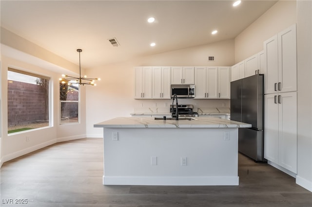 kitchen with light stone counters, visible vents, vaulted ceiling, appliances with stainless steel finishes, and white cabinetry