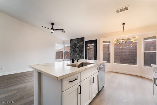 kitchen with visible vents, a sink, pendant lighting, stainless steel dishwasher, and light wood-type flooring