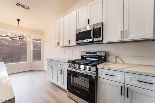 kitchen with light stone countertops, visible vents, light wood-style flooring, appliances with stainless steel finishes, and pendant lighting