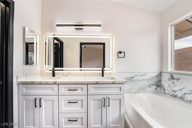 bathroom with double vanity, a garden tub, and a sink