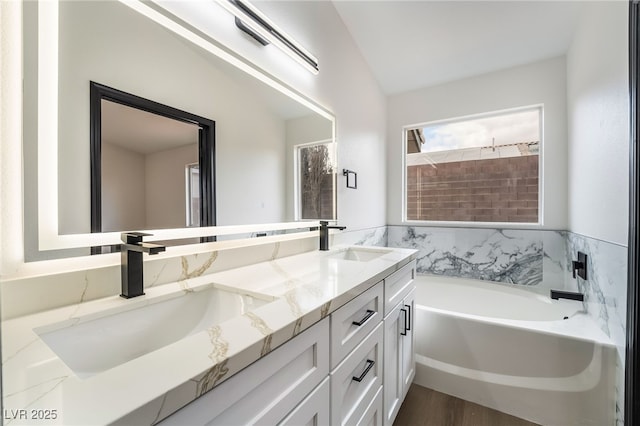 bathroom with double vanity, a garden tub, and a sink