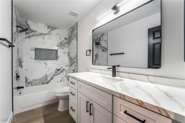 bathroom with visible vents, toilet, shower / tub combination, wood finished floors, and vanity