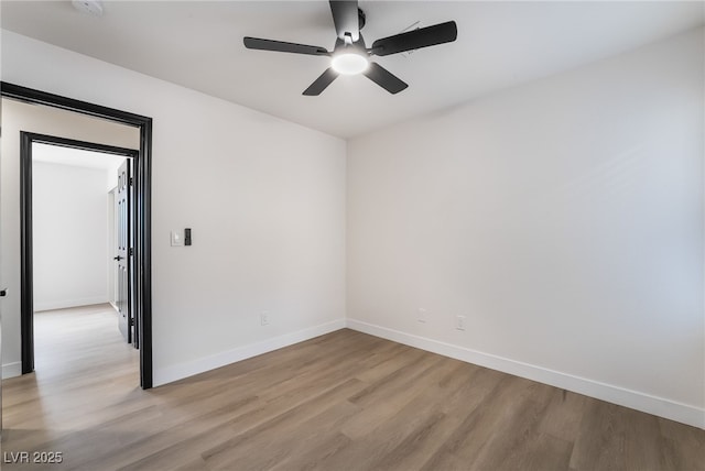 spare room with a ceiling fan, light wood-type flooring, and baseboards