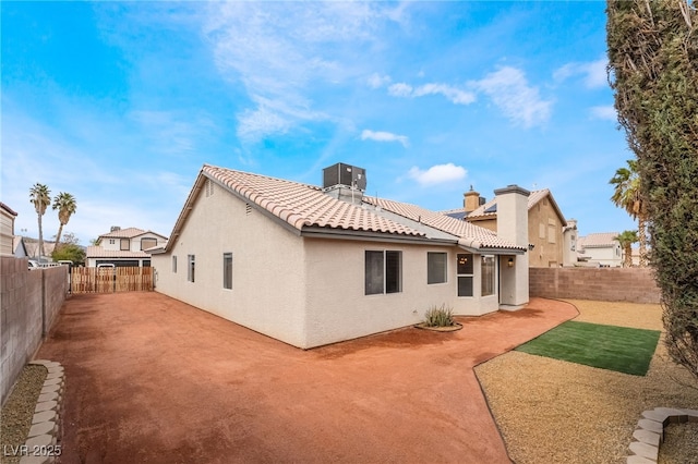 back of house with a fenced backyard, stucco siding, a tiled roof, and a patio