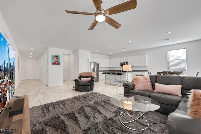 living area with visible vents, recessed lighting, light wood-type flooring, and ceiling fan