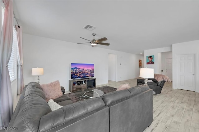 living area with visible vents, light wood-style flooring, and a ceiling fan