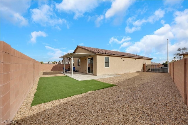 back of house with a fenced backyard, stucco siding, a tile roof, and a patio