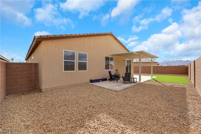 rear view of property featuring a patio area, stucco siding, a tiled roof, and a fenced backyard