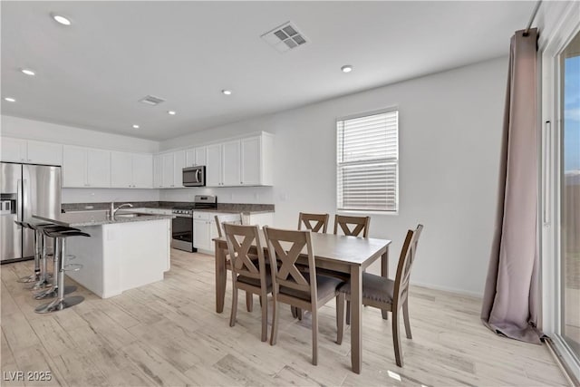 dining space with light wood-style flooring, recessed lighting, and visible vents