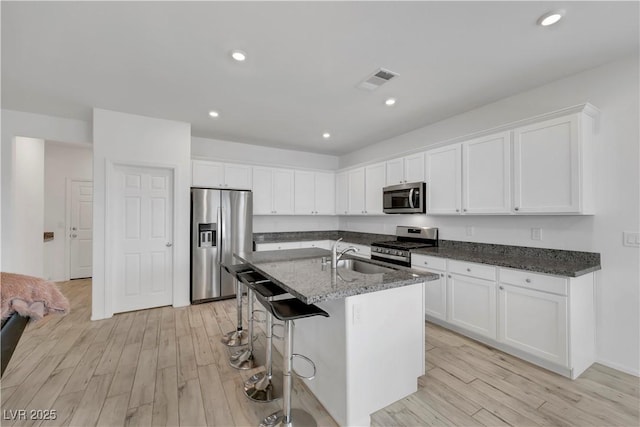 kitchen with visible vents, a sink, stainless steel appliances, light wood-style floors, and white cabinets