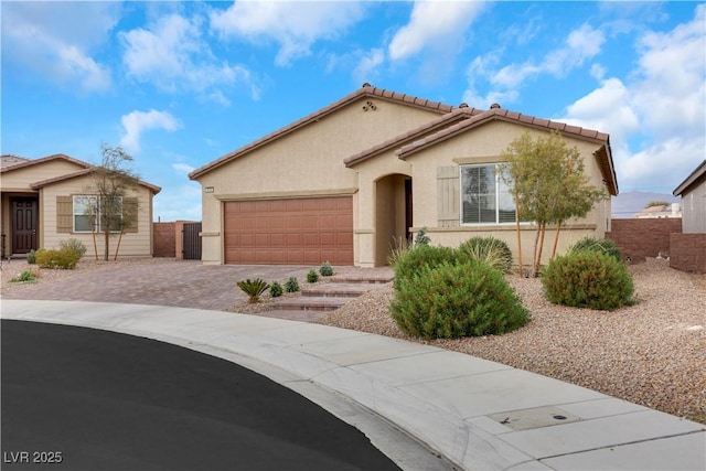 mediterranean / spanish-style home with fence, driveway, an attached garage, stucco siding, and a tile roof