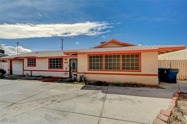 ranch-style home with stucco siding, driveway, an attached garage, and fence