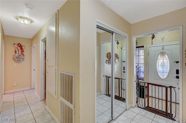 foyer entrance featuring light tile patterned floors, baseboards, and visible vents