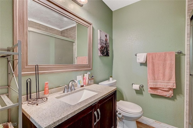 bathroom with a shower with door, toilet, vanity, and a textured wall