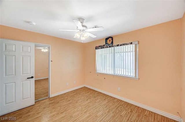 empty room with baseboards, ceiling fan, and light wood finished floors