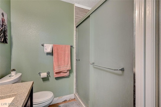 full bathroom featuring baseboards, toilet, a stall shower, and vanity