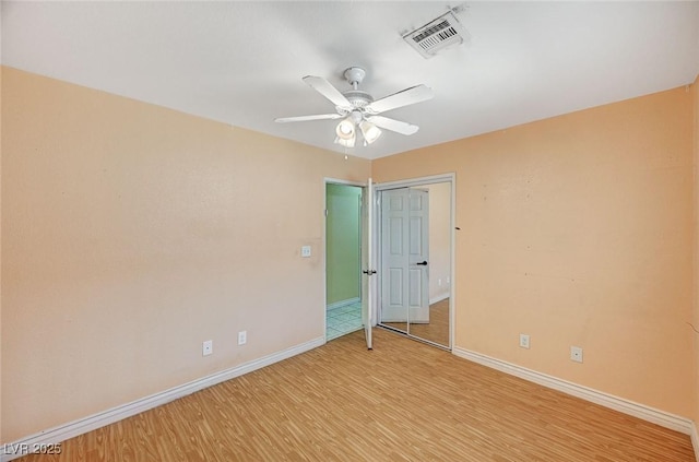 unfurnished bedroom featuring light wood-style floors, visible vents, a closet, and baseboards