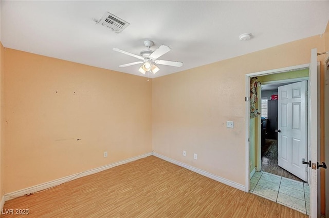 unfurnished room with ceiling fan, visible vents, baseboards, and wood finished floors