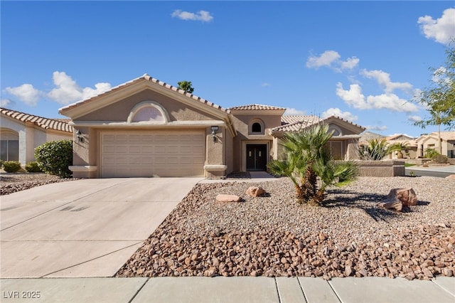 mediterranean / spanish house with stucco siding, concrete driveway, an attached garage, and a tiled roof