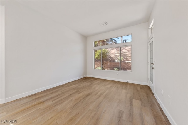 empty room featuring light wood-type flooring, baseboards, and visible vents