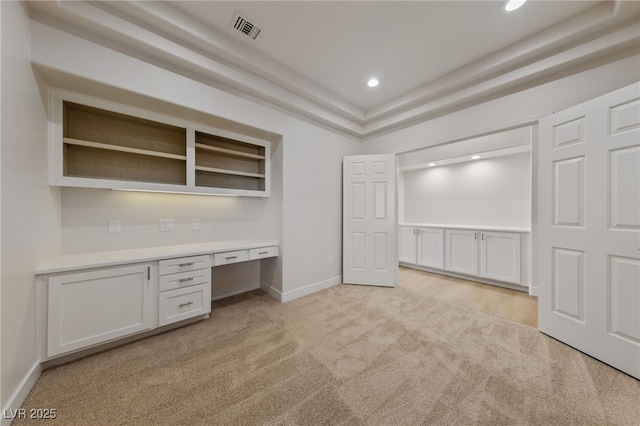 unfurnished office featuring visible vents, baseboards, recessed lighting, built in desk, and light colored carpet